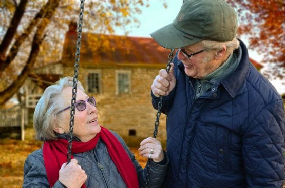 Two seniors enjoying a moment on a swing outdoors