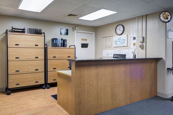 Reception area with wooden storage units and a clock