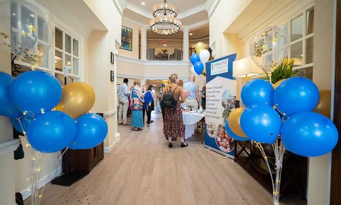 Residents and staff celebrating in a bright lobby with balloons