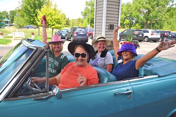 Residents enjoying a car ride with hats and smiles