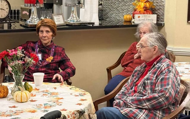 Residents seated in a common area with autumn decor