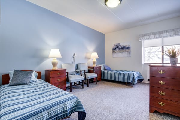 A well-furnished resident room with two beds and décor