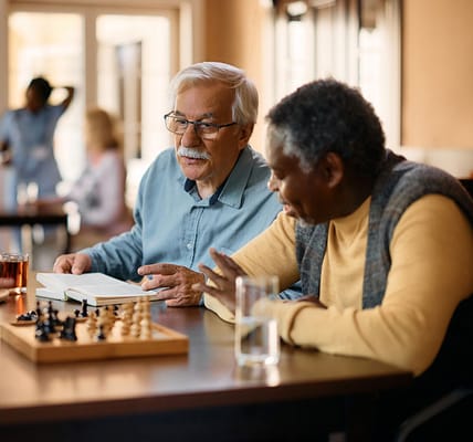 Two seniors playing chess in a common area