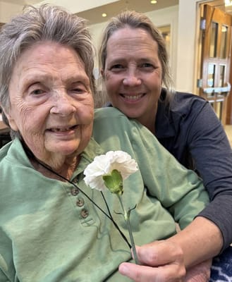 Resident and staff member posing with a flower
