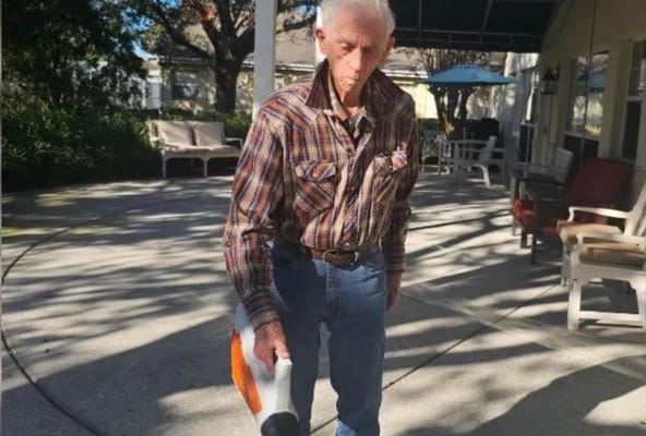 A resident outdoors using a leaf blower in the courtyard