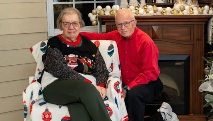 Two residents sitting together by a fireplace during the holidays