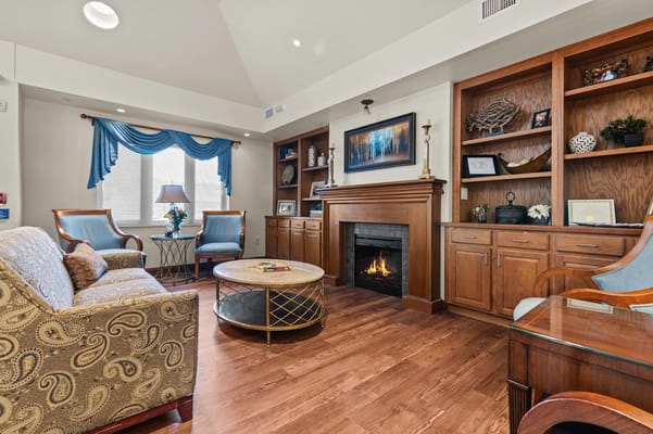 A cozy common area with seating around a fireplace