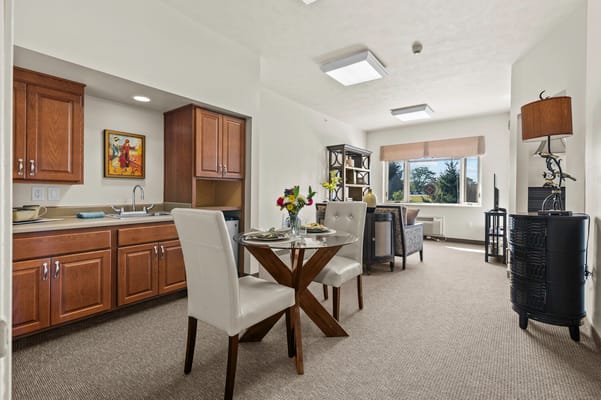 A cozy senior living room with a dining table and kitchenette