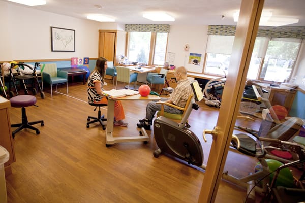 A staff member assisting a resident in a therapy room