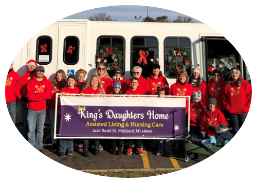 Group photo of staff and residents in festive sweaters outside the facility van
