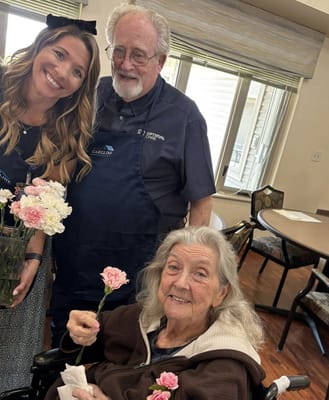 Residents and staff smiling together, holding flowers