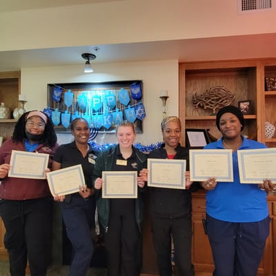 Staff holding certificates in a decorated common area