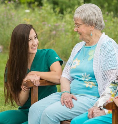 A caregiver and a resident smiling and chatting outdoors