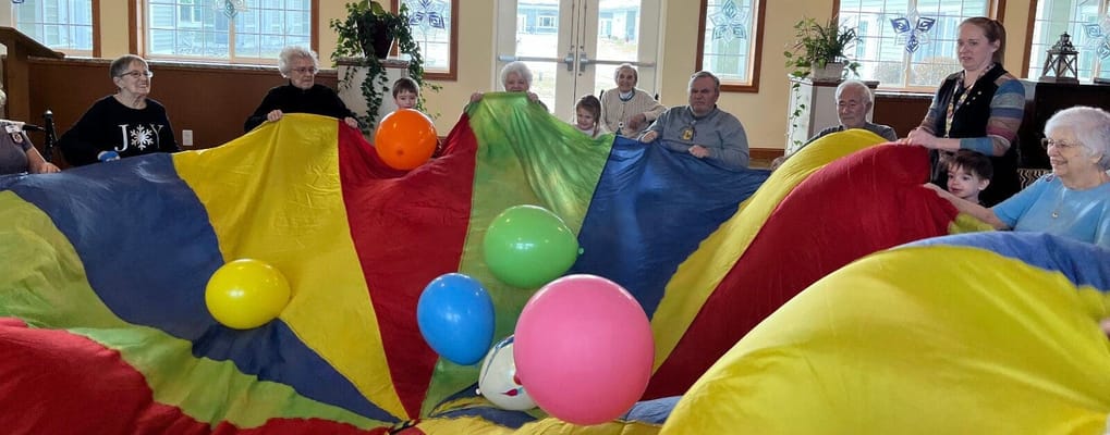 Residents and children enjoying a group activity with colorful parachute