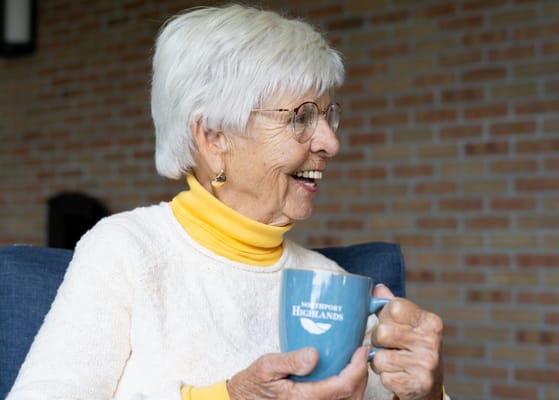 A senior woman smiling with a coffee mug