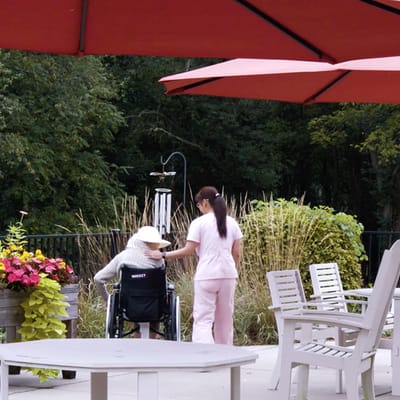 Caregiver assisting resident outdoors in a garden area