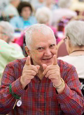 Senior resident smiling and posing with fingers pointing.