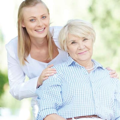 A caregiver with a smiling resident outdoors