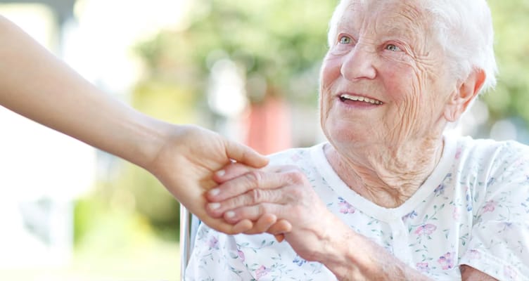 A resident smiling while holding hands with a caregiver