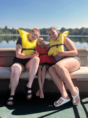 Three people wearing life jackets on a boat