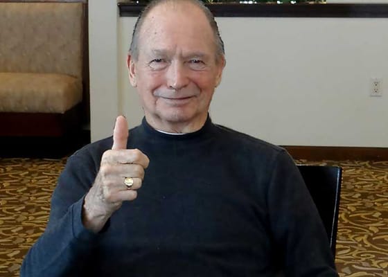 Resident giving a thumbs up in a lounge area