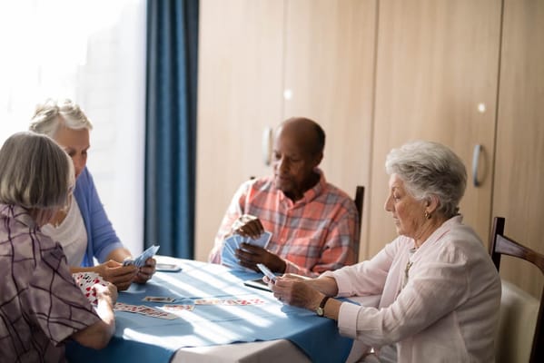 Residents playing cards around a table in an activity room