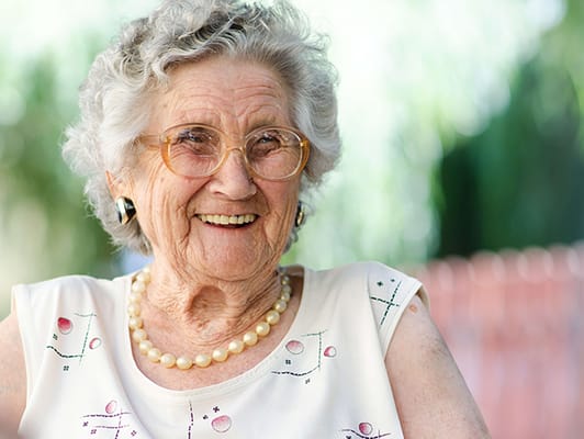Smiling elderly woman with glasses outdoors