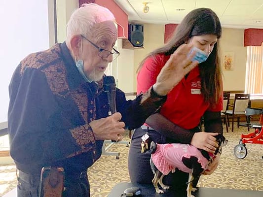 Resident interacting with staff and dogs in an activity room