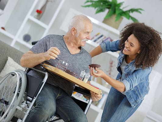 Caregiver offering a snack to a resident in a common area.