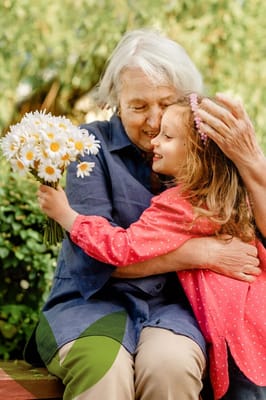Elderly woman embracing a young girl holding flowers