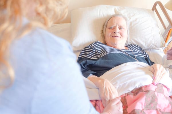 A resident smiling while interacting with a caregiver in bed