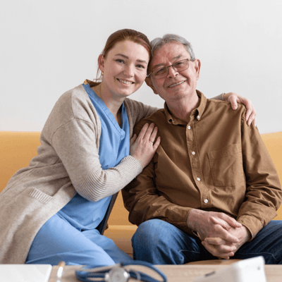 A caregiver and resident smiling together on a couch