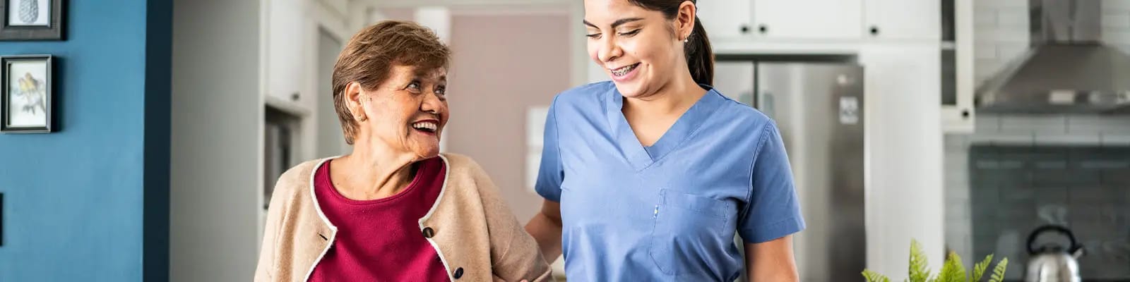 A caregiver assisting a smiling resident in a bright interior