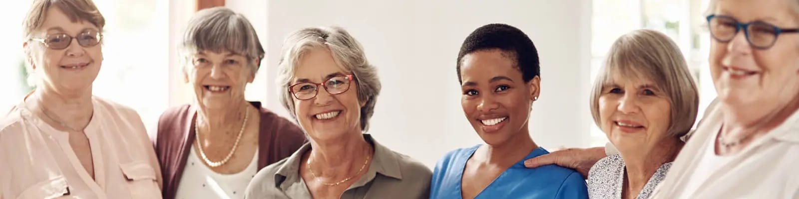 Residents and staff smiling together in a bright common area