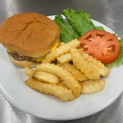 Plate of food with a cheeseburger, fries, lettuce, and tomato