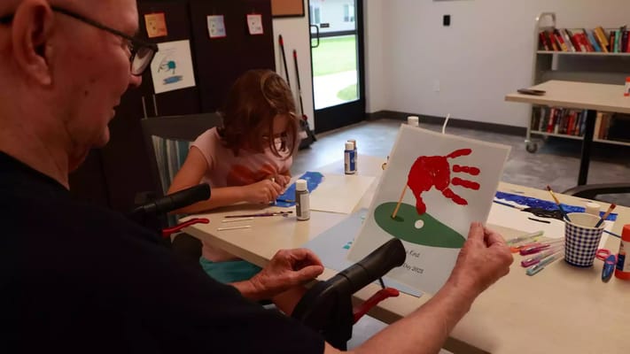 A resident holding an art project with a child in an activity room