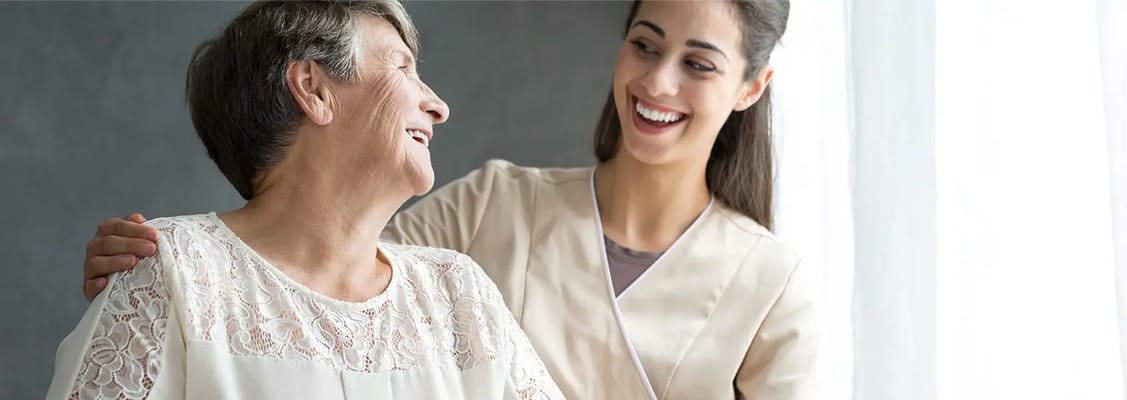 A caregiver smiling with a resident indoors
