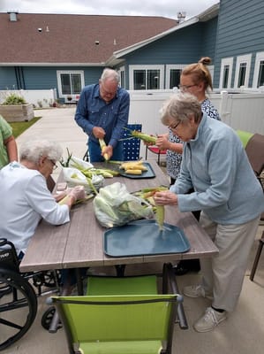 Residents and staff preparing corn outdoors