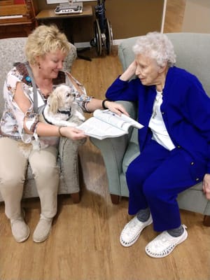 Staff member reading with resident and pet dog