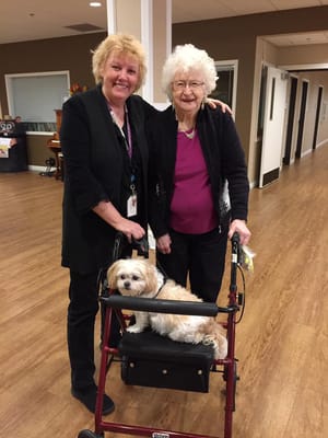 Staff member and resident posing together with a dog