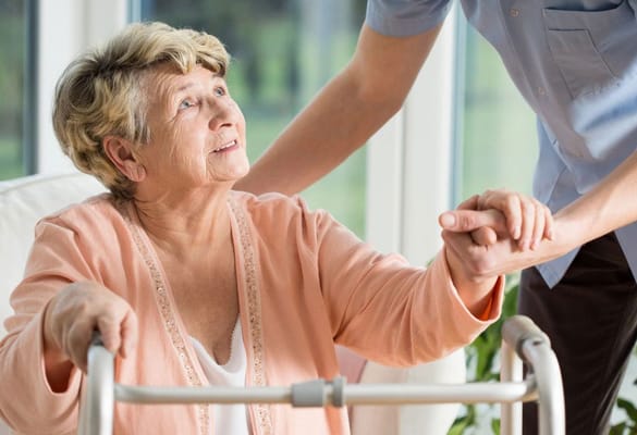 Caregiver assisting a senior woman with a walker