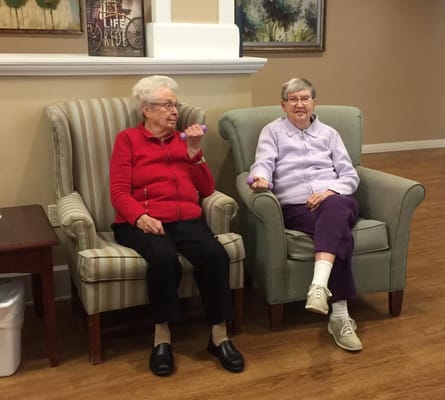 Two residents sitting in comfortable chairs in a common area