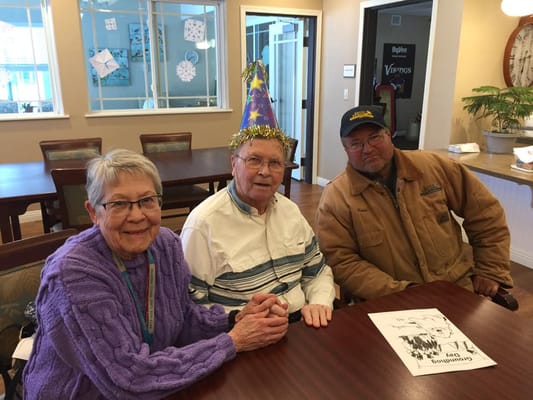 Residents celebrating with party hats in an activity room