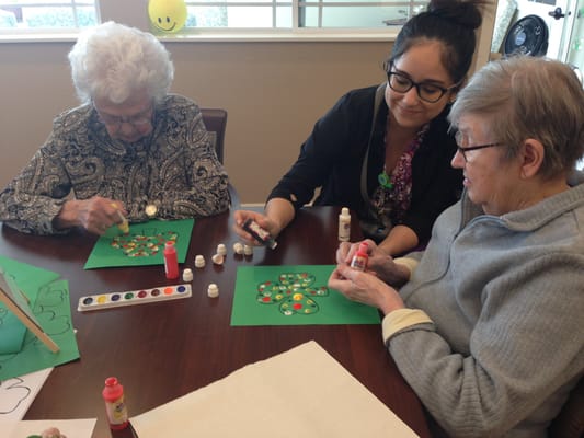 Residents engaged in an arts and crafts activity with a caregiver