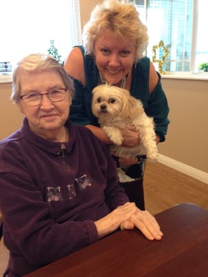 A staff member posing with a resident and a dog