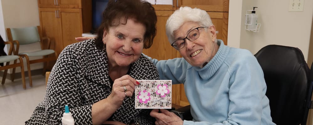 Two residents smiling and holding a card together