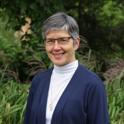 A smiling staff member in a green outdoor space