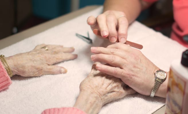 Senior resident receiving a manicure from staff