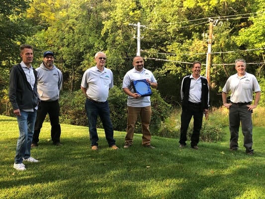 Group of staff members standing outdoors in a grassy area