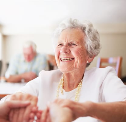 A smiling elderly woman engaging with a caregiver
